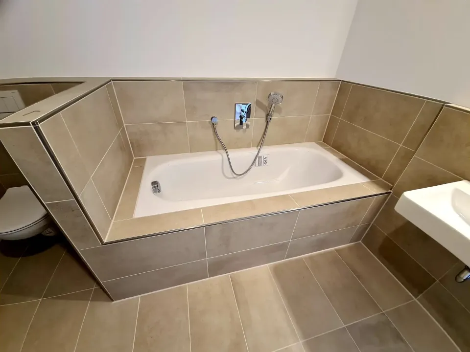 Gefliester Badewannenrand mit neuen Fugen in Beige
